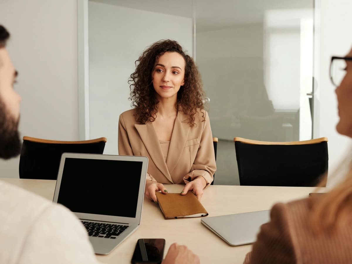 Woman in a formal office meeting with two colleagues, engaging in conversation about mental health support.