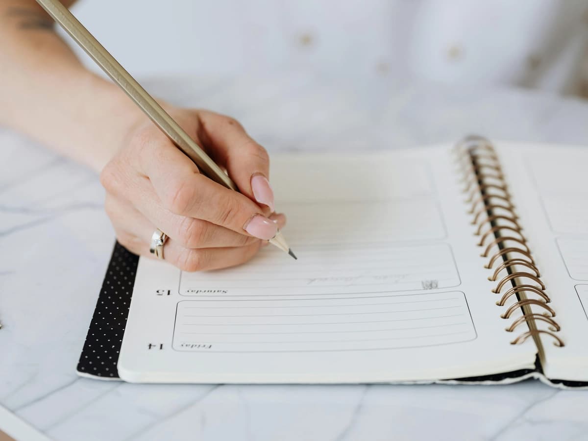 Hand writing notes in a planner about ADHD.