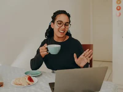 A woman with ADHD enjoys a video call, sipping tea and smiling warmly