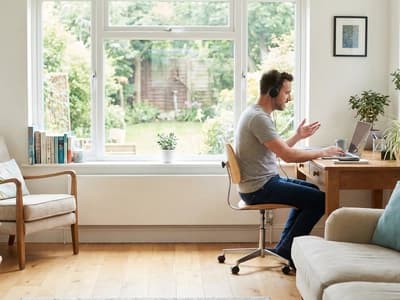Working remotely in a calm, bright room. Using headphones helps block environmental noise, aiding focus for individuals with ADHD